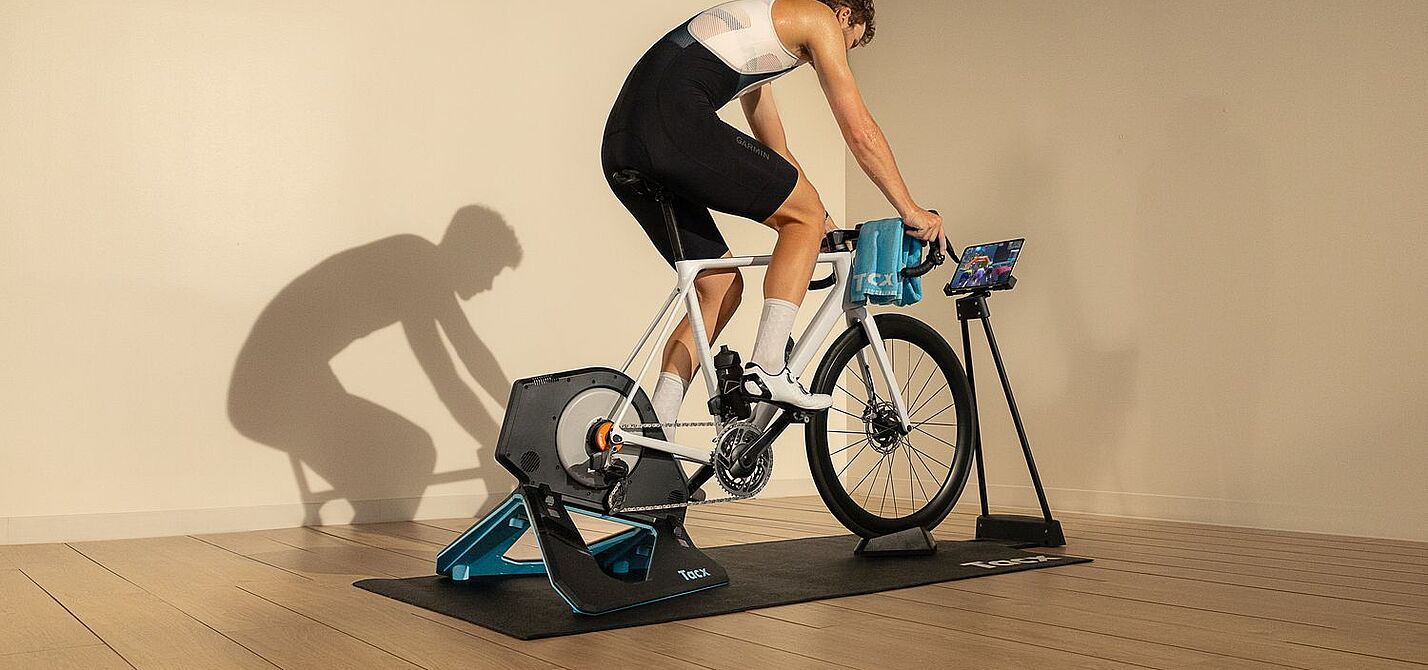Tacx Neo 2T Ein Radfahrer sitzt in einem Raum auf einem auf einem Smarttrainer montierten Rennrad.