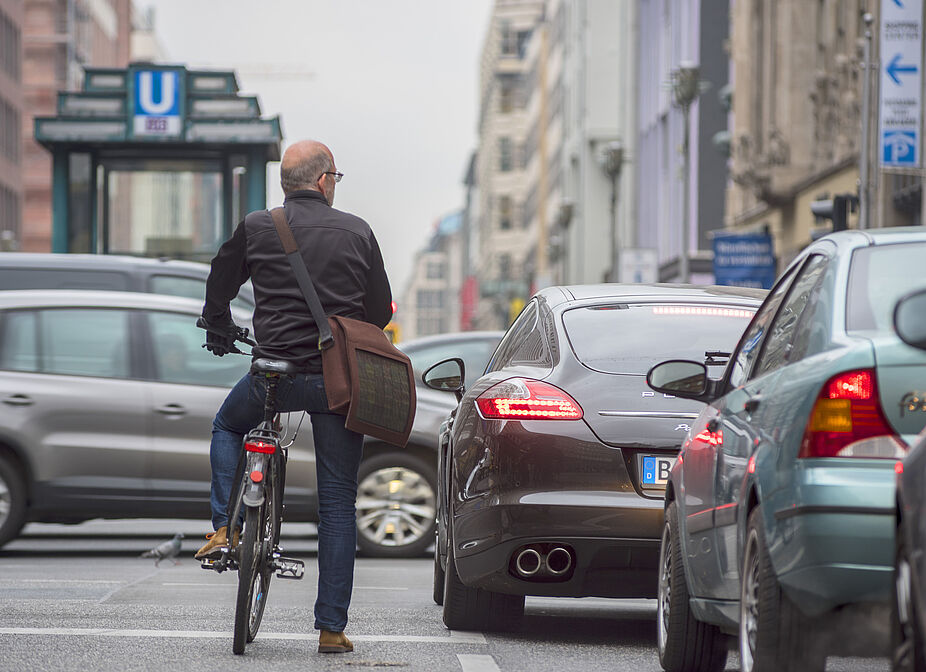 Fahrradfahren im dichten Autoverkehr Mann auf einem Rad steht zwischen Autos